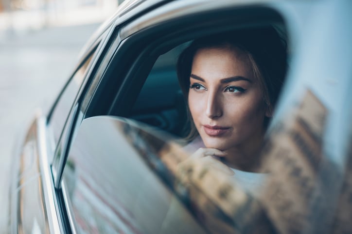Young woman on the back seat of a car looking out of the window.